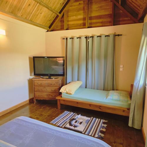 a small bedroom with a bed and a tv at Bienvenue chez Gaston in Le Tampon