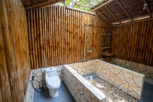 a bathroom with a toilet and a wooden wall at Pemimpi Sumba in Lambatama
