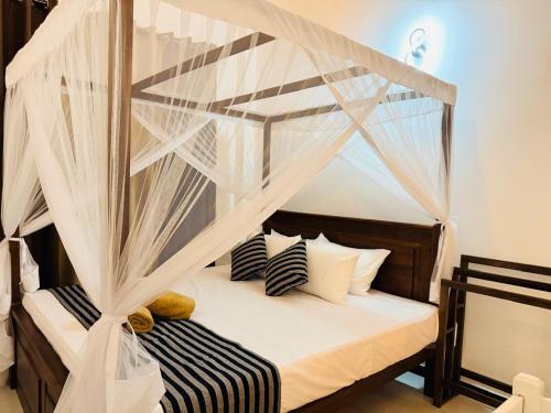 a bedroom with a canopy bed with white curtains at Sunset Villa in Dickwella
