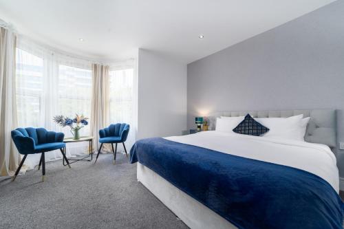 a bedroom with a large bed and two blue chairs at Harbour Hub Hotel in Southampton