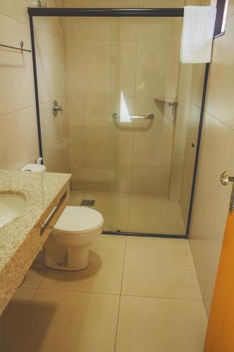 a bathroom with a shower and a toilet and a sink at Grande Hotel Guarapuava in Guarapuava