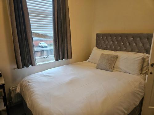 a bed in a room with a window and a bed with white sheets at Comfort, Convenience & Style in Preston