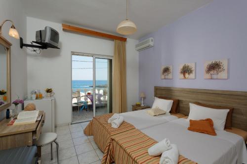 a bedroom with two beds and a view of the ocean at Zorbas Hotel in Hersonissos