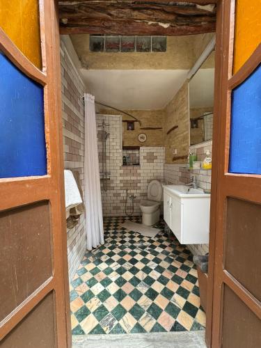 a bathroom with a toilet and a checkered floor at Suite Printemps Ryan in Kairouan