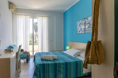 a blue bedroom with a bed and a desk at Hotel Baia Del Sole in Marina di Ragusa