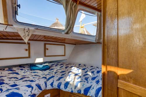 a bed in a small room with a window at Bateau Gré - Sur le quai in Saint-Gilles