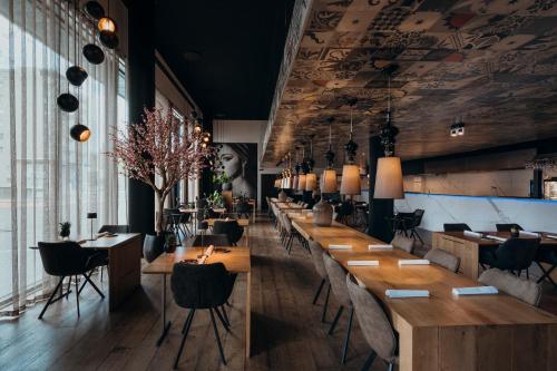 un ristorante con tavoli e sedie in legno e una parete di finestre di Carbon Hotel a Genk