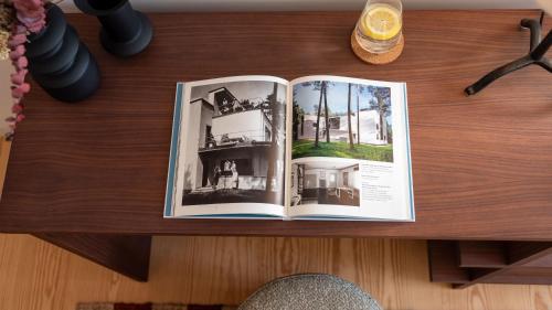 an open book on a wooden table with a drink at Ando Living - São Miguel House in Porto
