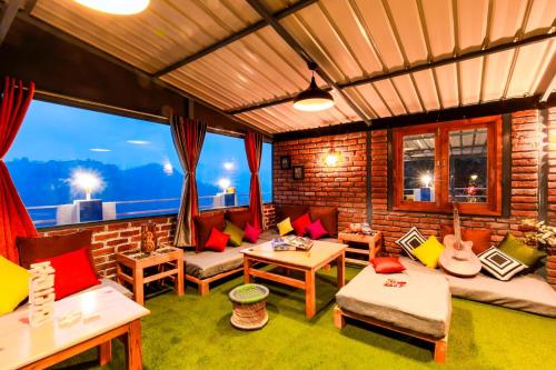 a living room with couches and tables and windows at PACK Mukteshwar in Mukteshwar