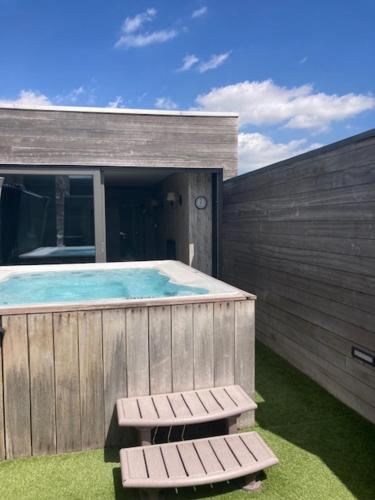 een zwembad met twee banken naast een gebouw bij La vie en Roos in Maldegem