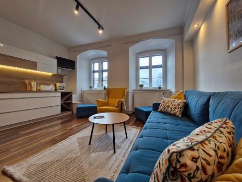 een woonkamer met een blauwe bank en een tafel bij Várker39 Apartman in Sopron