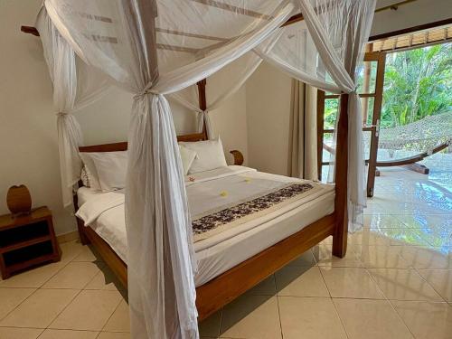 een slaapkamer met een hemelbed bij Beachfront Villa Nirwana with Private Jacuzzi in Pengastulan