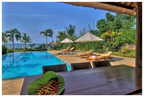 - une vue sur la piscine avec une table et des chaises dans l'établissement Beachfront Villa Nirwana with Private Jacuzzi, à Pengastulan
