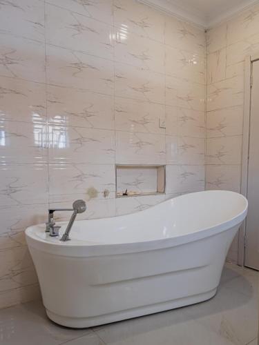 a white bath tub in a bathroom with marble walls at Virginia Apartments in Addo