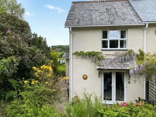 een wit huis met bloemen ervoor bij Lower Axford Cottage in Callington