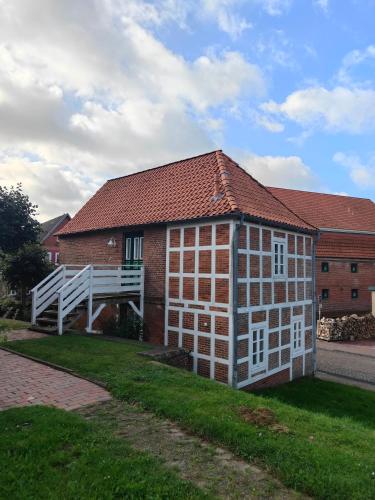 a brick building with a white door and a bridge at Kleines Schleusenwärterhaus am Ostedeich in Neuhaus an der Oste