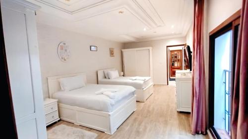 a white bedroom with two beds and a window at 3 bedroom Nijma large authentic Moroccan apartment in Tangier