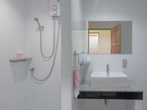 ein weißes Badezimmer mit Waschbecken und Dusche in der Unterkunft อัมพวารี Amphawaree Hotel in Samut Songkhram