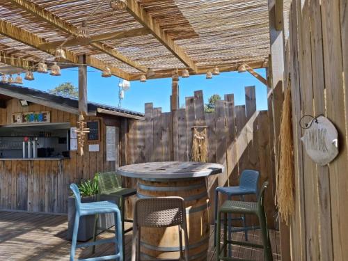 een patio met een tafel en stoelen op een houten terras bij Le Clos des Genets in Quend