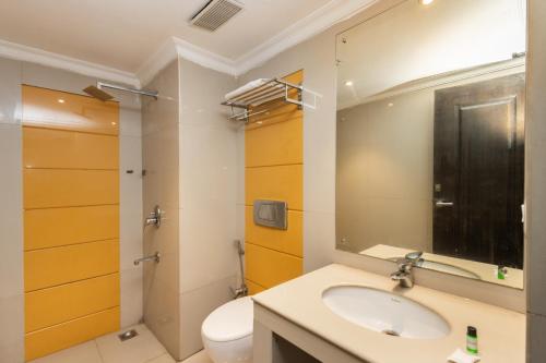 a bathroom with a sink and a toilet and a mirror at The Senate Hotel By Addon Group in Cochin