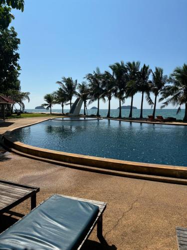 a large swimming pool with palm trees and the ocean at Sea view house, swimming pool in Ko Chang