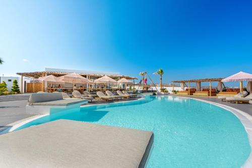 a swimming pool with lounge chairs and umbrellas at The Amethyst Exclusive Suites Oia in Oia