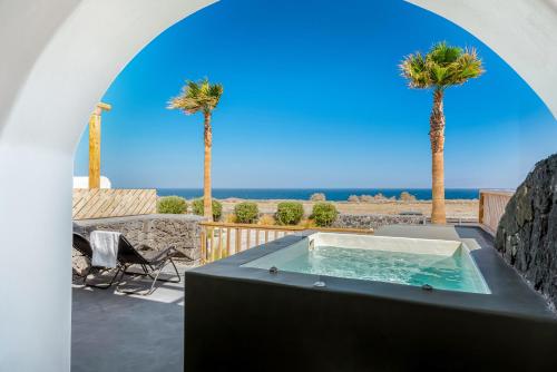 a hot tub on a patio with palm trees at The Amethyst Exclusive Suites Oia in Oia