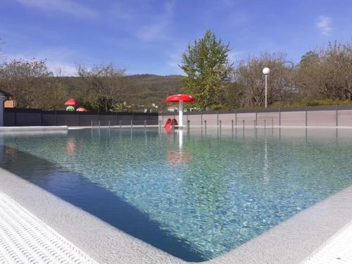 a swimming pool with a red umbrella in the water at ZEcamping 4 étoiles dog friendly bien-être restaurant et soirées animées in Foix