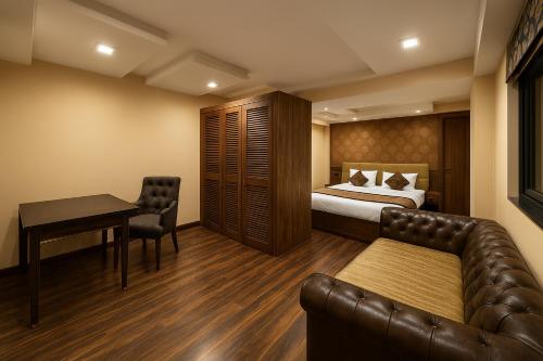 a bedroom with a bed and a table and a couch at Arcadian Hotel in Gangtok