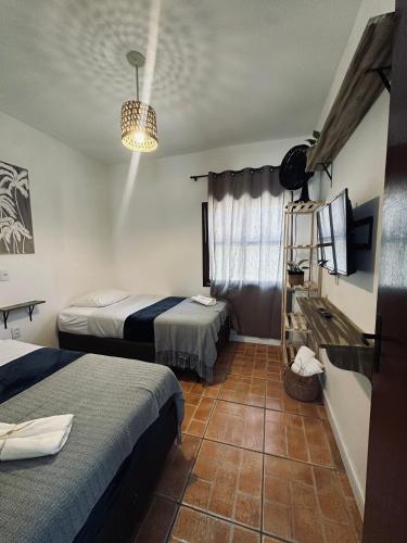 a hotel room with two beds and a television at Ar do Mar in Florianópolis