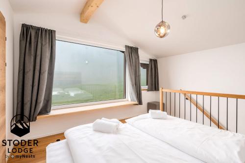 two beds in a room with a large window at StoderLodge - Alpine Garden Residence - by myNests in Gröbming