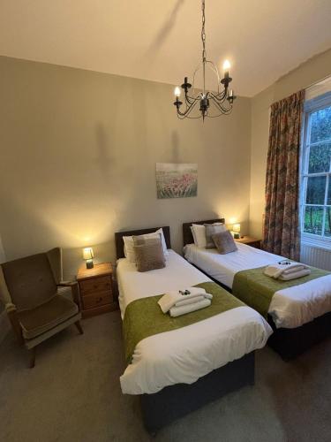 a bedroom with two beds and a chair and a chandelier at Garden House Stamford in Stamford