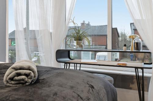 a bedroom with a bed with a table and a window at Lovely 4b Stay- Ideal for Contractors & Families in Bury