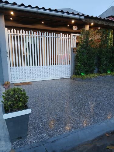 een wit hek voor een huis bij Casa aconchegante e familiar em Matinhos in Matinhos