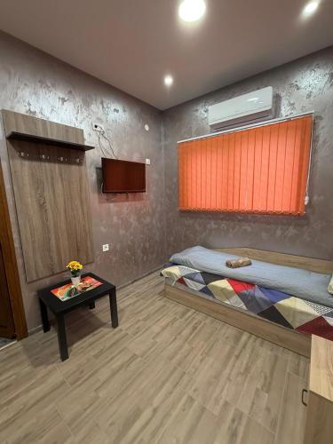 a room with two beds and a table in it at Квартири ЦЕНТРАЛ in Dolna Mitropoliya