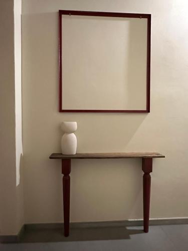 a mirror on a wall with a vase on a table at Noua Living - Boutique Apartments Ravenna Centro in Ravenna