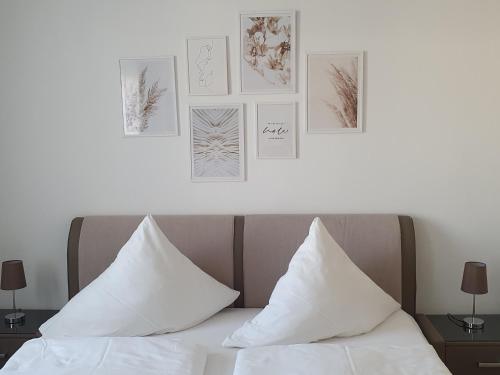 ein Bett mit weißen Kissen und Bildern an der Wand in der Unterkunft Pension Clara in Tanneberg