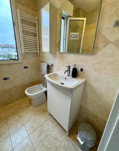 a bathroom with a sink and a toilet and a mirror at AppArt 24 city center parking and Sea Design district in Lignano Sabbiadoro