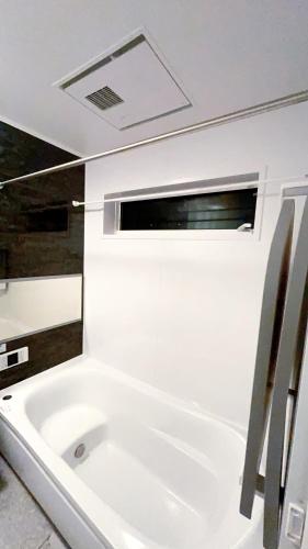 a white bath tub in a bathroom with a window at Tokyo Hoshino House 1Floor in Tokyo