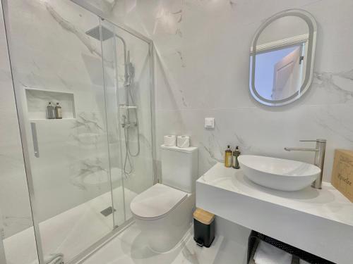 ein weißes Badezimmer mit Waschbecken und Dusche in der Unterkunft Espada Preta Apartments in Câmara de Lobos