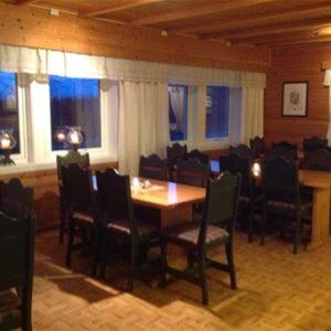 a dining room with a table and chairs and windows at Lapphaugen Turiststasjon in Tennevoll