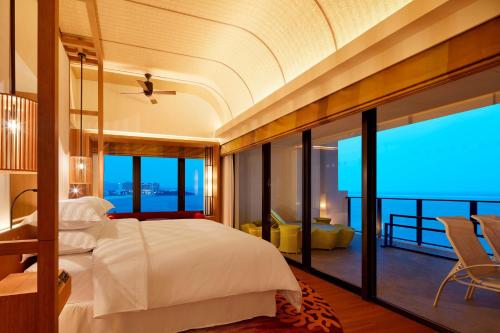 a bedroom with a large bed and a balcony at Sheraton Okinawa Sunmarina Resort in Onna
