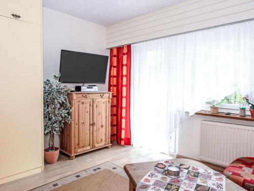 a living room with a television and a red curtain at Apartment Am Birkenhain-28 by Interhome in Seefeld in Tirol