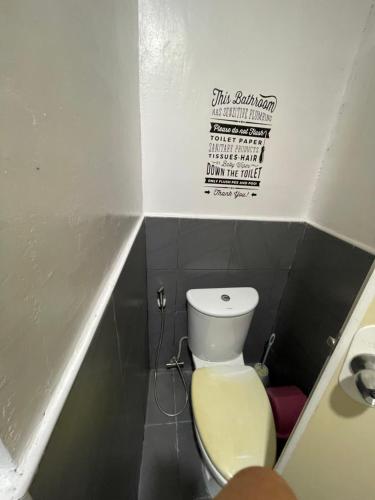 a small bathroom with a toilet and a sign on the wall at Casa Alegria Beach Rooms in Alegria