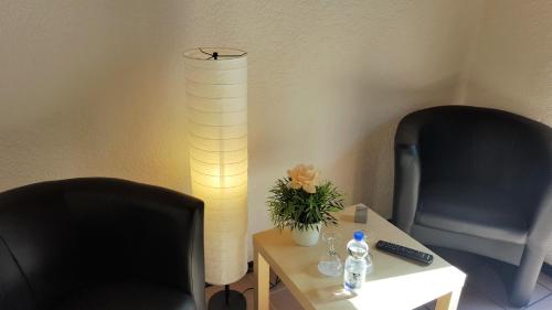 two chairs and a table with a vase of flowers and a lamp at Hotel Exquisite in Bobenheim am Berg