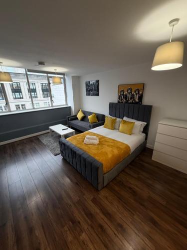 a bedroom with a large bed and a couch at Stunning City View Studio Apartment by StaySavvy Accommodation in Liverpool