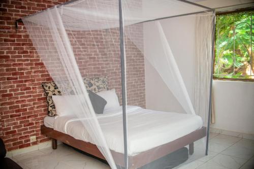 Ein Bett mit Himmelbett in einem Zimmer mit einer Backsteinwand in der Unterkunft Alfords Villa 