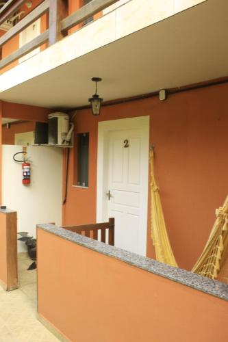 a building with an orange wall with a white door at Pousada Mar & Vida e Doçaria in Paraty