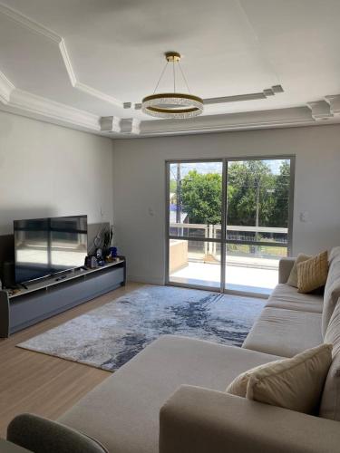 een woonkamer met een bank en een flatscreen-tv bij Apto centro de Ametista do Sul 2 dorm in Ametista do Sul