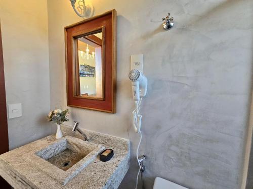 een badkamer met een wastafel en een haardroger bij Vila Bella Suítes - Conforto no Centro in Carrancas